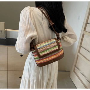 Detail of colorful striped woven straw bag with brown leather base and logo text