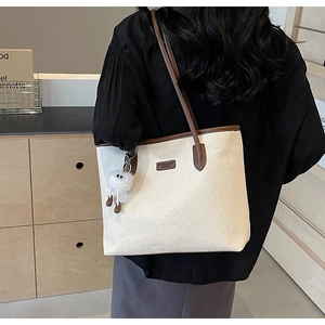 Detail of off-white tote bag with vintage embossed texture and brown shoulder strap