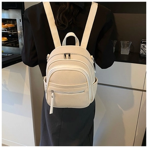 Lifestyle shot of a mini cream canvas backpack worn by a model in a modern kitchen
