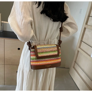 Close-up of colorful straw crossbody bag with contrast leather trim and knot strap detail