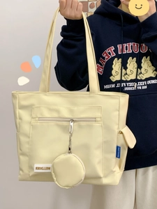 Detail of cream nylon tote bag with functional pockets and mini coin purse charm