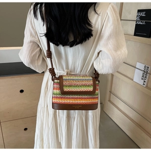 Detail of multi-color woven straw crossbody bag with leather strap on a female model