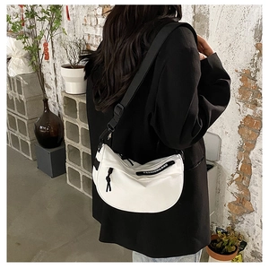 Detail of white crescent saddle bag showing black strap and fashion zipper branding