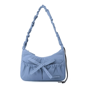 Detail of light blue nylon tote bag showing bow decoration and ruched strap texture