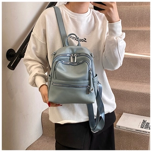 Close-up of a light blue mini backpack with multiple zipper pockets on a female model