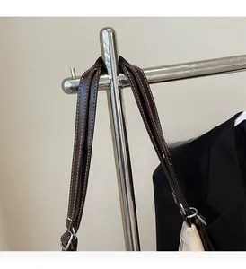 Detail of dark brown leather strap with white stitching and silver metal hardware hook