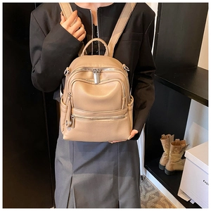Detail of khaki pebbled faux leather backpack showing multiple zipper compartments