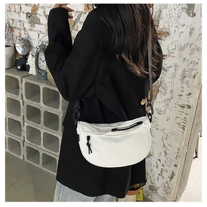 White nylon saddle bag with adjustable black strap and fashion ribbon detail shown on model