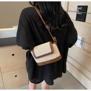 Detail shot of a contrast straw woven crossbody bag with brown leather trim on a model