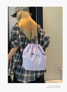 Detail of light purple nylon drawstring bucket backpack on model with focus on stitching