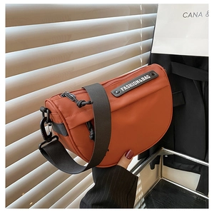 Detail of orange nylon saddle bag with wide strap and fashion logo text label