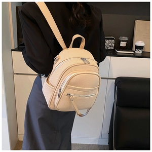 Detail of a beige woven texture backpack with multiple zip pockets on a casual lifestyle setting