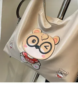 Close-up of beige tote bag with cute cartoon bear print and stylish metal chain strap