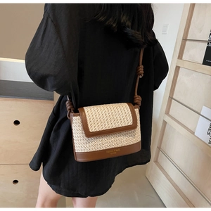 Detail of straw crossbody bag with brown leather trim and decorative knot on strap
