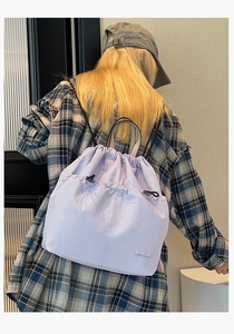 Detail of light purple nylon drawstring backpack with metal logo and adjustable straps