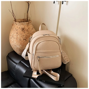 Detail of beige woven backpack featuring stylish wave pattern wide strap and multi-zipper pockets