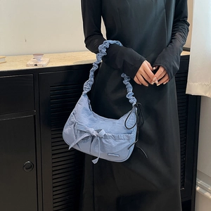 Detail of light blue nylon tote bag featuring bow decoration and ruffled shoulder strap