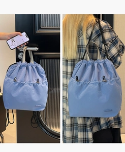 Detail of light blue nylon drawstring backpack showing dual hand and shoulder straps