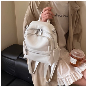 Close-up of white lychee leather backpack showing silver zippers and adjustable straps