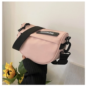 Detail of pink nylon saddle bag with adjustable black wide strap and rubber fashion tag