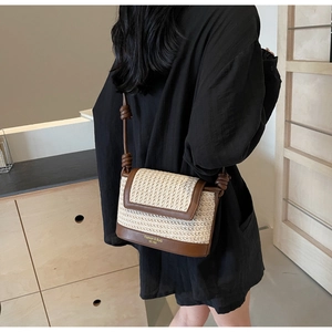 Detail of retro straw crossbody bag with brown leather trim and knotted shoulder strap
