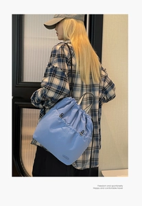 Detail of light blue drawstring backpack with front pockets and slim black straps