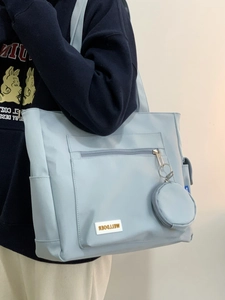 Detail of light blue tote bag with matching mini pouch and branded rubber logo patch
