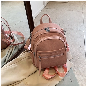 Detail of pink mini backpack featuring textured fabric and woven wave pattern straps