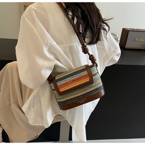 Detailed close-up of handmade rainbow woven crossbody bag with leather trim and logo