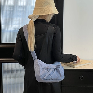 Close-up of light blue nylon tote bag with large bow and pleated drawstring texture