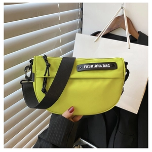 Detail of neon green nylon saddle bag with wide black strap and fashion logo