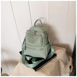 Close-up of mint green leather backpack featuring multiple metal zippers and textured finish
