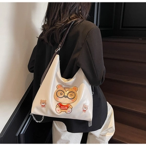 Close-up of white tote bag with cute cartoon bear print and stylish metal chain strap