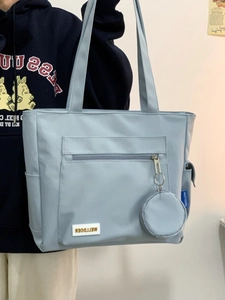 Detail of light blue tote bag featuring functional front zipper and small round coin purse