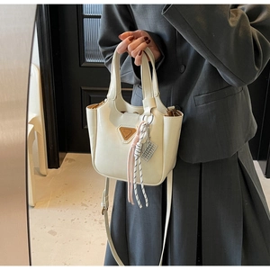 Détail du sac à main en similicuir crème avec plaque en métal et charme tissé par mannequin