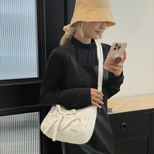 Detail view of white nylon tote bag with bow decoration and pleated texture on shoulder strap