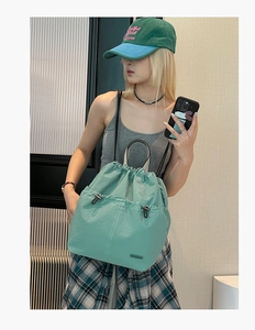 Detail of mint green nylon backpack showing drawstring closure and buckled front pockets