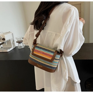 Close-up of a colorful woven straw crossbody bag with brown leather details and knots