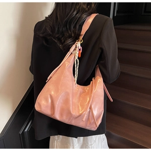 Sac hobo rose verni avec chaîne en acrylique et glands porté à l'épaule pour femme