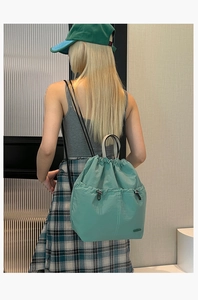 Detail of light green nylon drawstring backpack with adjustable buckle pockets on back