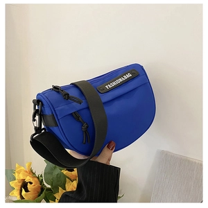 Detail of royal blue nylon saddle bag featuring an adjustable wide black shoulder strap