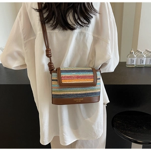 Detail of multi-color woven straw crossbody bag with brown leather strap and knot accent