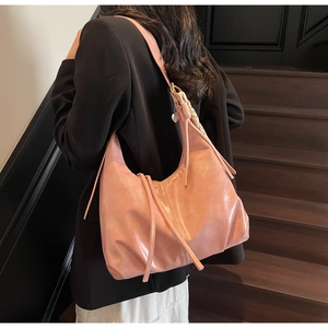 Détail du grand sac hobo rose avec coutures, nœud décoratif et breloque cœur sur l'anse