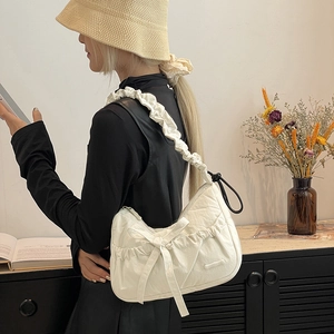 Detail of white nylon tote bag with bow accent and ruffled strap worn by a model