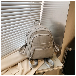 Detail of light gray canvas backpack with geometric patterned straps and silver zippers