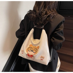 Close-up of white patent leather tote bag with cute cartoon bear embroidery detail
