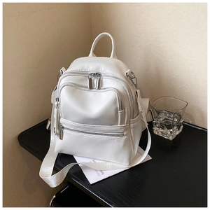 Close-up of white pebble leather texture and silver zipper detail on stylish backpack