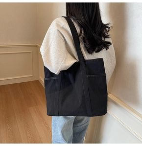 Detailansicht einer schwarzen Canvas-Tragetasche mit Seitentaschen an einem Model