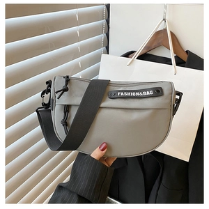 Detail of grey nylon saddle bag featuring a wide strap and knotted zipper tassel