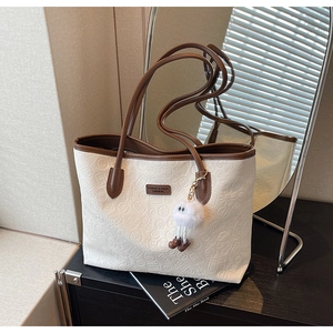 Detail of embossed leather tote bag with white faux fur charm and brown handles